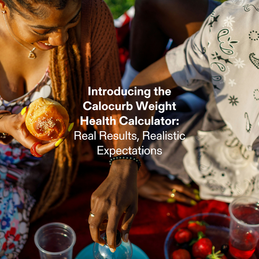 A lifestyle image of two people enjoying food outdoors on a picnic blanket, with one person holding a bread roll and another reaching for a drink.