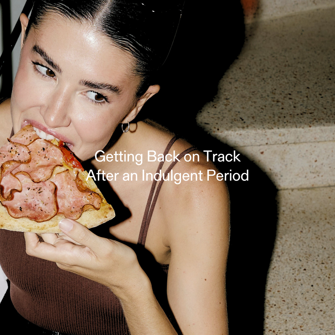 Woman eating a slice of pizza, representing indulgence and getting back on track after overeating or cravings