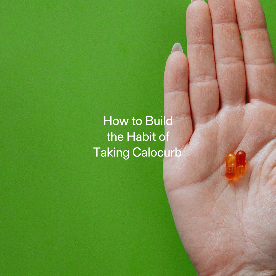 Hand holding two Calocurb capsules against a green background, symbolizing habit formation and daily supplement routine